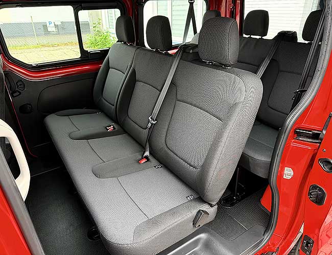 Rear passenger bench seats in black fabric inside the red Renault Trafic minibus