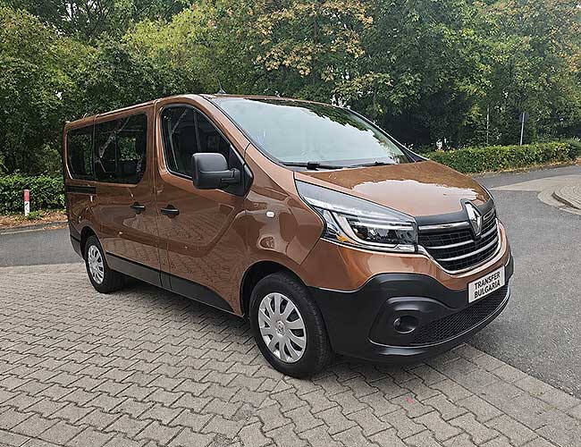 Bronze Renault Trafic minibus, front three-quarter view, parked on paved courtyard