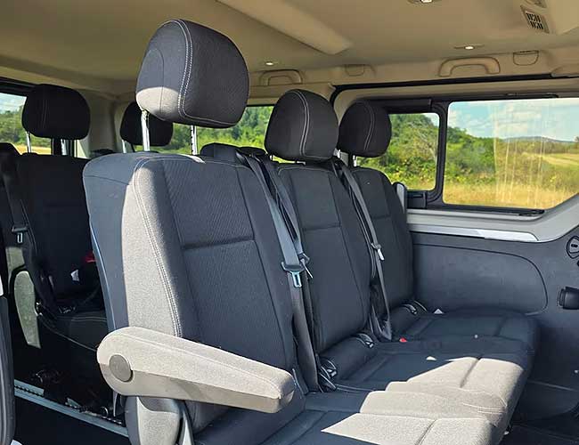 Passenger seats and window view of the countryside inside the Renault Trafic minibus