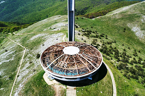 Aerial view of the round UFO-shaped Buzludzha Monument on a grassy mountain ridge in Bulgaria