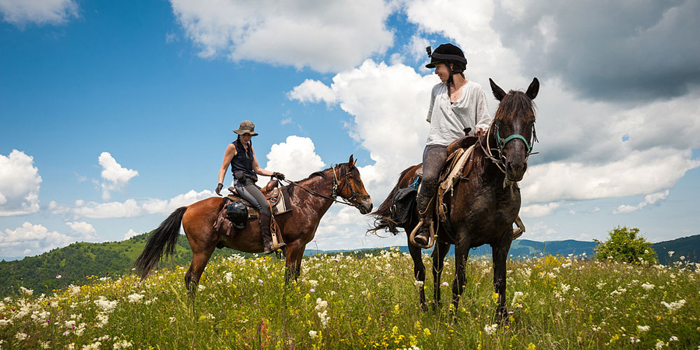 Horse riders on a mountain trail approaching Glozhene Monastery in the Balkan Mountains near Teteven